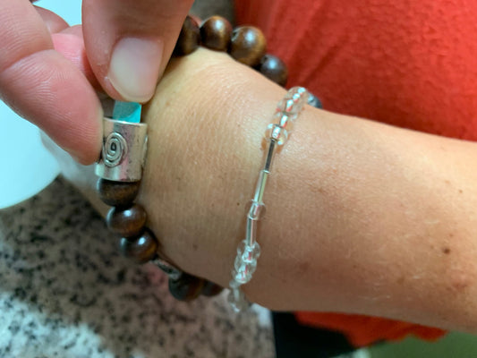Wooden lava stone diffuser bracelet and crystal bracelet with Manifesting Barrel worn on a wrist